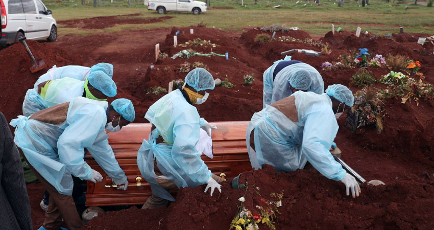 Trabajadores funerarios con equipo de protección personal llevan un ataúd durante el entierro de una víctima de covid-19. Foto: Cortesía/El País.